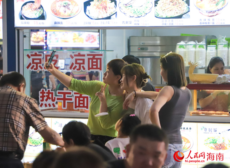 幾位游客在夜市打卡拍照。人民網(wǎng) 牛良玉攝