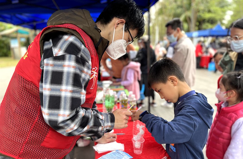 2023年世界濕地日主題游園宣傳活動現(xiàn)場，志愿者與小朋友共同模擬濕地在自然中凈化水質(zhì)的過程。