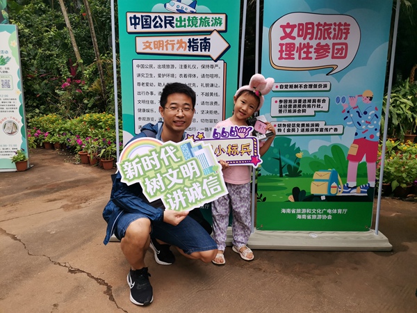 游客手拿文明旅游標識牌打卡。海南省旅游協(xié)會供圖