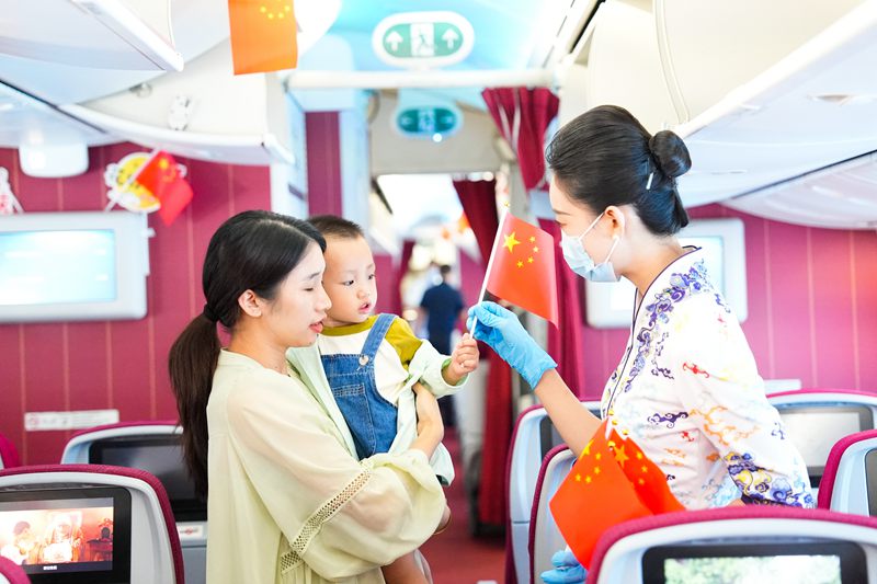 10月1日，海南航空乘務(wù)員為機(jī)上旅客發(fā)放小國旗。海南航空供圖.jpg