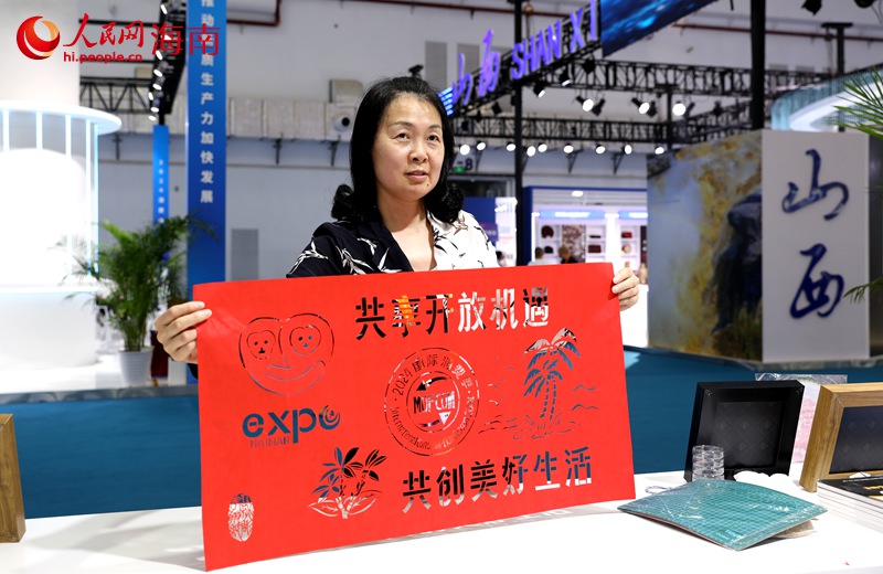 湖北仙桃雕花剪紙技藝人展示消博會主題剪紙。人民網(wǎng)記者 符武平攝