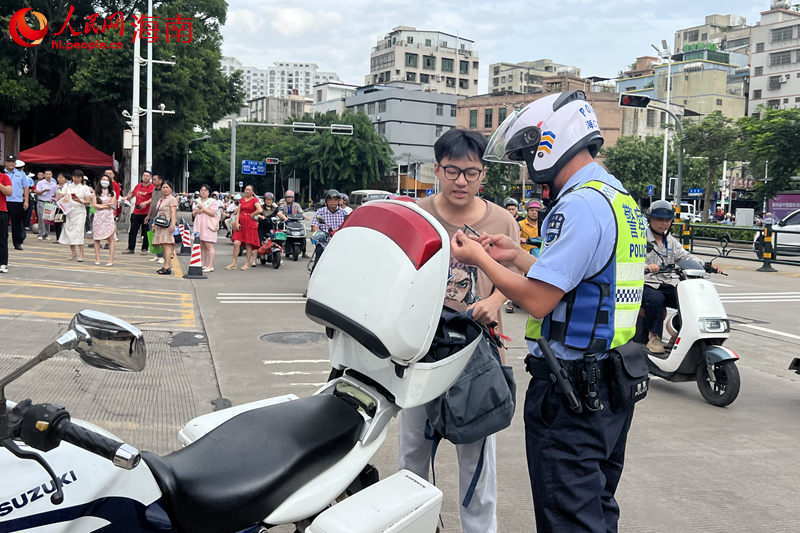 在海南省農墾中學考點，交警載著考生取回身份證后返回考點。 人民網記者 李學山攝