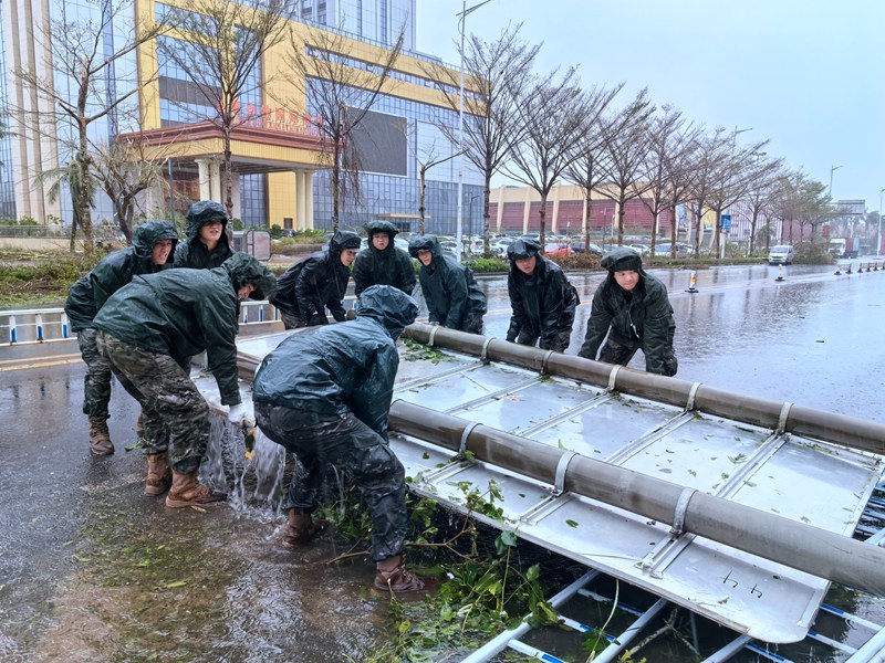 武警?？谥ш?duì)官兵正在移除被風(fēng)吹到的路邊指示牌。房立攝