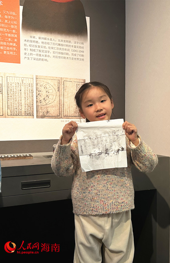 小女孩展示剛剛通過雕版印刷互動(dòng)裝置獲得的拓印宣紙。人民網(wǎng) 劉楊攝