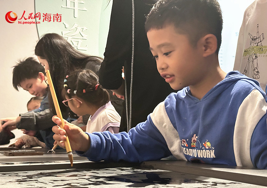 小朋友在“文明載體——古代造紙印刷”單元體驗雕版印刷互動裝置。人民網(wǎng) 劉楊攝