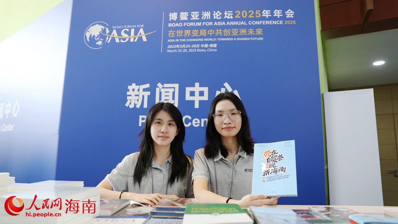 在博鰲亞洲論壇新聞中心，工作人員向參會(huì)嘉賓和媒體記者推薦“營(yíng)”在自貿(mào)港，“畫”說(shuō)新海南宣傳冊(cè)。人民網(wǎng)記者符武平攝