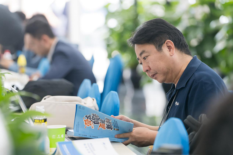 3月25日，在年會新聞中心工作區(qū)，參加年會報道工作的記者在閱讀《“營”在自貿(mào)港“畫”說新海南》中英文漫畫冊。海南省營商環(huán)境建設(shè)廳供圖