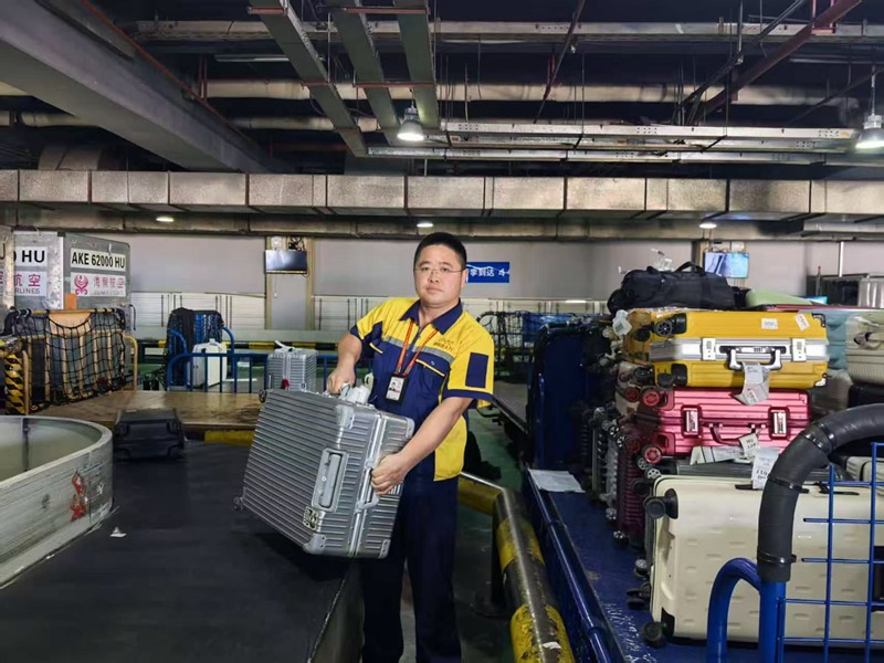 王鑫分揀行李。三亞鳳凰國際機(jī)場供圖