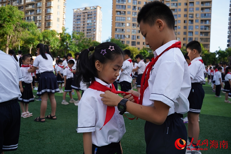 老隊(duì)員為新隊(duì)員系上紅領(lǐng)巾。人民網(wǎng)記者 毛雷攝